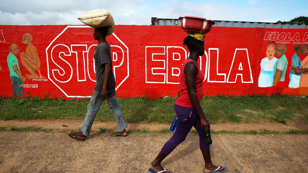People pass an Ebola awareness mural on October 2, 2014 in Monrovia, Liberia.
