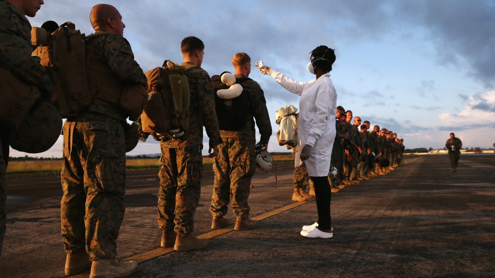 A health worker takes the temperature of U.S. Marines arriving to take part in Operation United Assistance on Oct. 9, 2014 near Monrovia, Liberia. (Photo by John Moore/Getty)