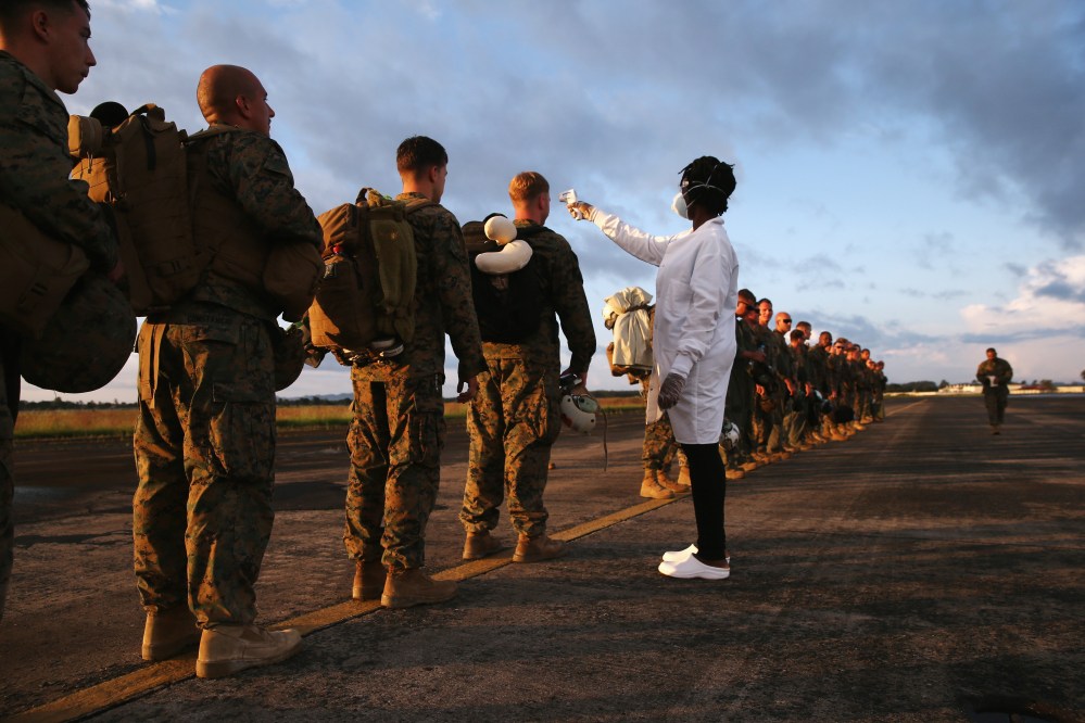 A health worker takes the temperature of U.S. Marines arriving to take part in Operation United Assistance on Oct. 9, 2014 near Monrovia, Liberia. (Photo by John Moore/Getty)