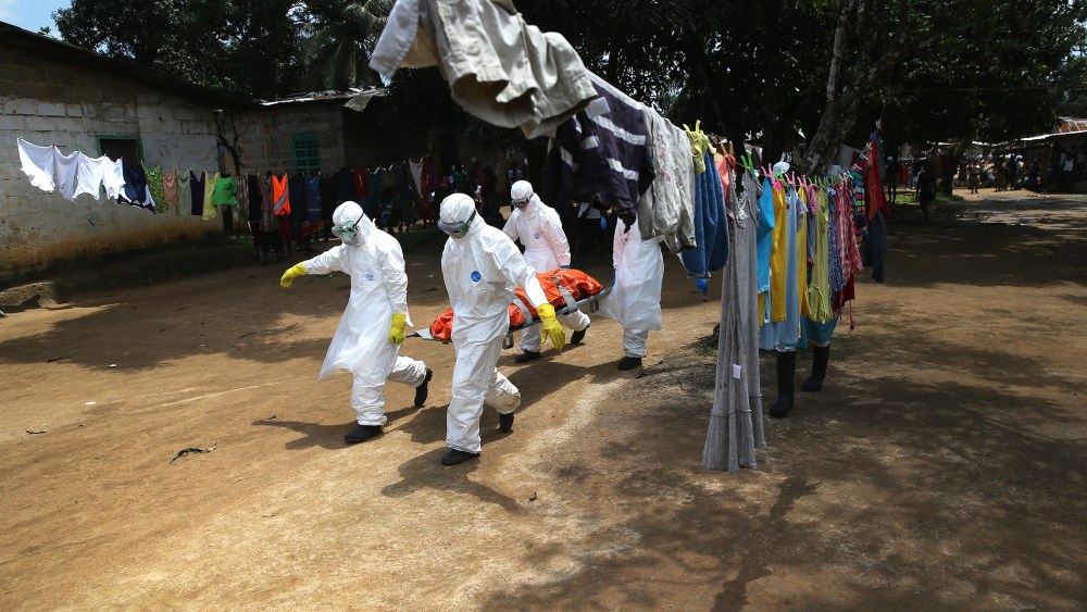 An Ebola burial team carries the body of a woman from a home in the New Kru Town suburb on Oct. 10, 2014 in Monrovia, Liberia. (Photo by John Moore/Getty)