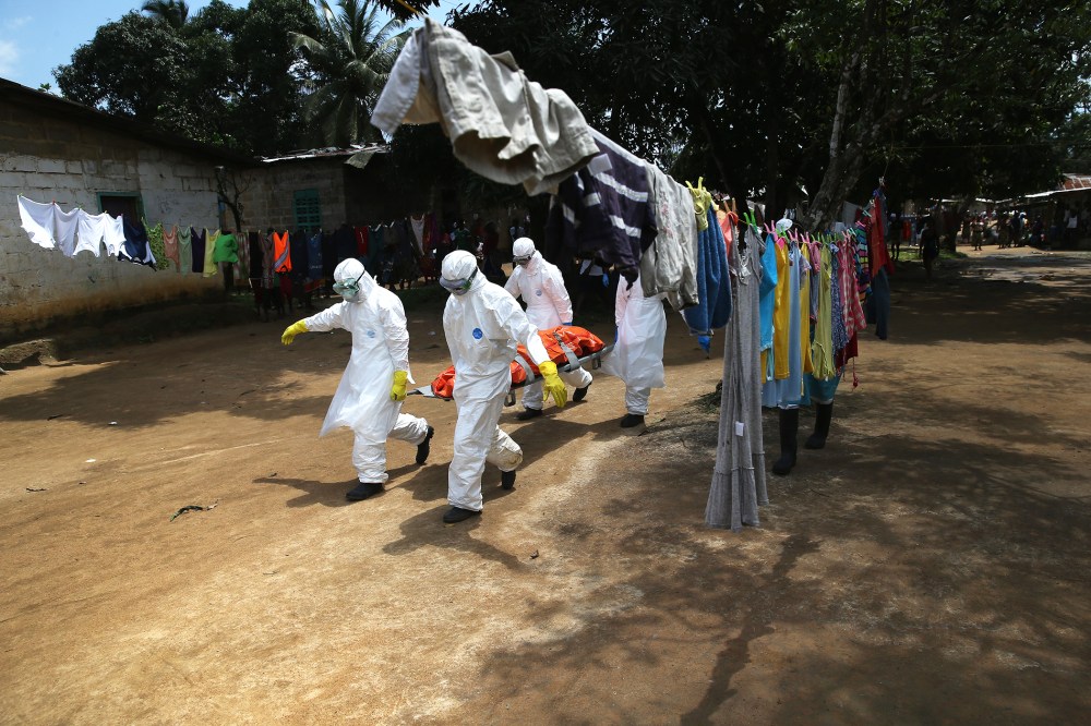 An Ebola burial team carries the body of a woman from a home in the New Kru Town suburb on Oct. 10, 2014 in Monrovia, Liberia. (Photo by John Moore/Getty)