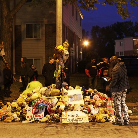 Demonstrators stand near a makeshift memorial for Michael Brown on Oct., 11 2014 in Ferguson, Mo. (Photo by Joshua Lott/AFP/Getty)