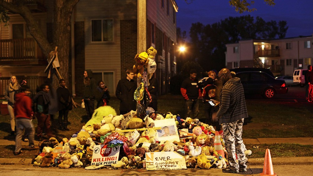 Demonstrators stand near a makeshift memorial for Michael Brown on Oct., 11 2014 in Ferguson, Mo. (Photo by Joshua Lott/AFP/Getty)