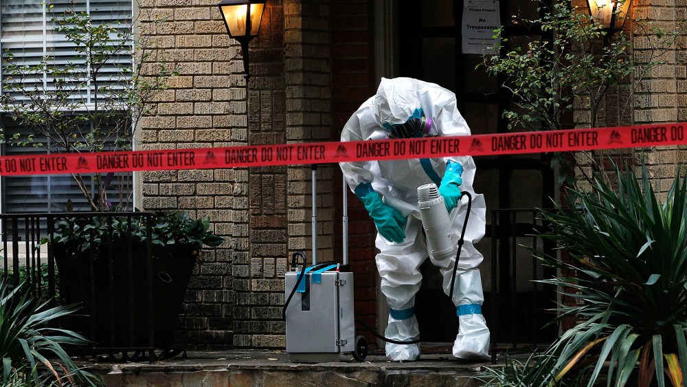 A man dressed in protective hazmat clothing treats the front porch of an apartment where a second person diagnosed with the Ebola virus resides on Oct. 12, 2014 in Dallas, Texas. (Photo by Mike Stone/Getty)