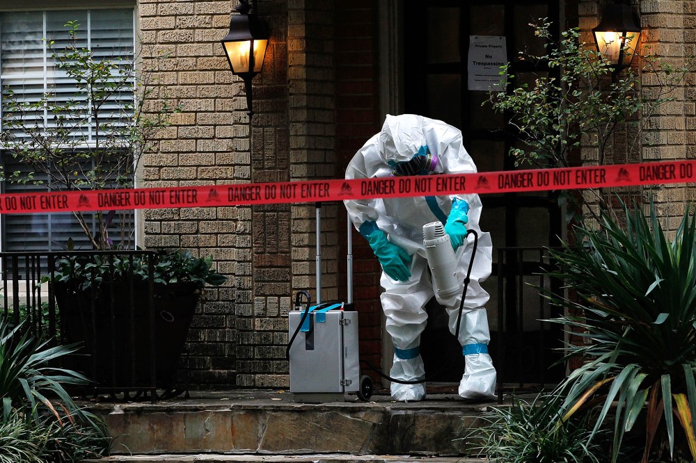 A man dressed in protective hazmat clothing treats the front porch of an apartment where a second person diagnosed with the Ebola virus resides on Oct. 12, 2014 in Dallas, Texas. (Photo by Mike Stone/Getty)