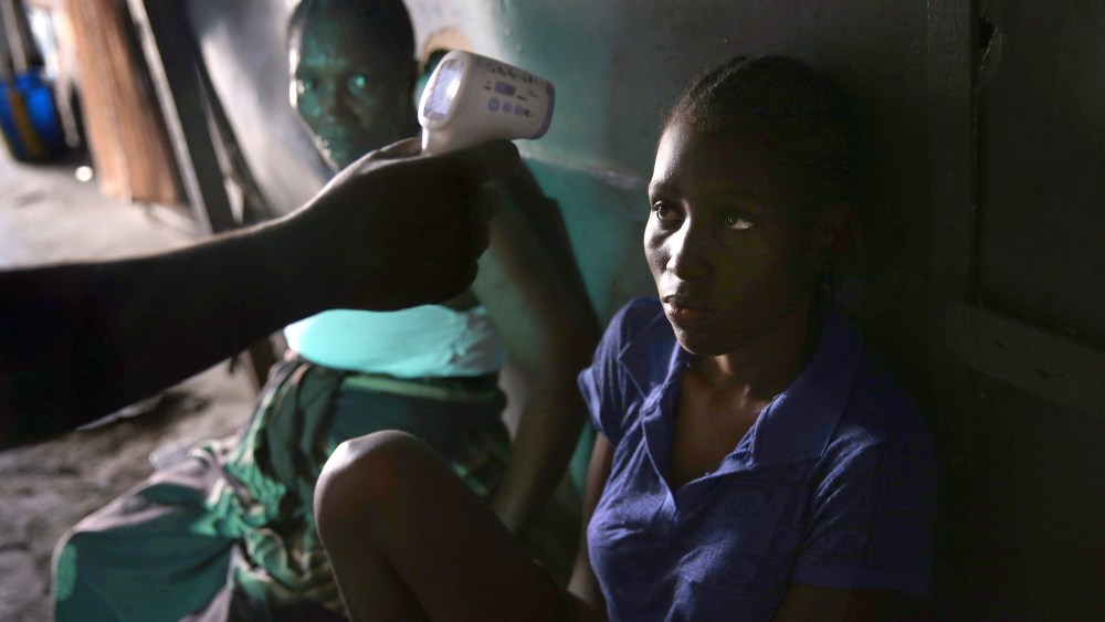 An Ebola tracing coordinator checks the temperature of Jessica Sompon, 17, finding her to have a fever in the West Point neighborhood on October 17, 2014 in Monrovia, Liberia.