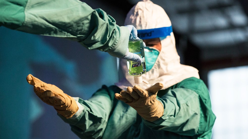 A nurse and a doctor demonstrate to health care professionals how to properly put on protective medical gear when working with someone infected with the ebola virus on Oct. 21, 2014 in New York, N.Y. (Photo by Andrew Burton/Getty)