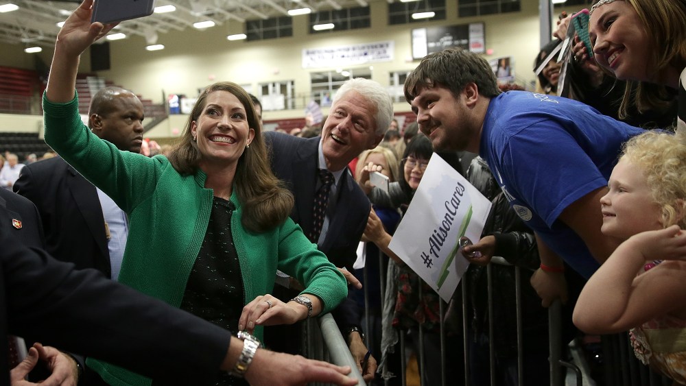Former U.S. President Bill Clinton (C) and U.S. Senate Democratic candidate and Kentucky Secretary of State Alison Lundergan Grimes (L) take a "selfie" with Kentucky voters after they spoke at a rally Oct. 21, 2014 in Paducah, Ky.