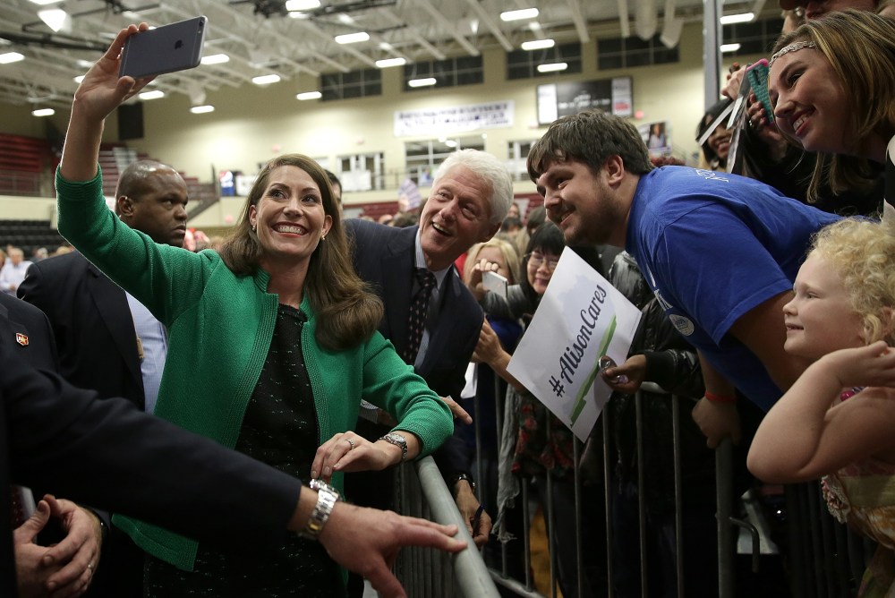 Former U.S. President Bill Clinton (C) and U.S. Senate Democratic candidate and Kentucky Secretary of State Alison Lundergan Grimes (L) take a "selfie" with Kentucky voters after they spoke at a rally Oct. 21, 2014 in Paducah, Ky.