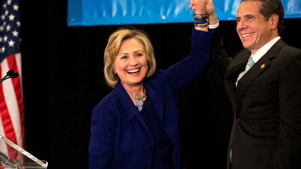 Former U.S. Secretary of State and U.S. Sen. Hillary Rodham Clinton (left) raises the hand of incumbent New York Governor Andrew Cuomo (right) laugh during a "Women for Cuomo" campaign event on Oct. 23, 2014 in New York, NY. (Photo by Bryan Thomas/Getty)