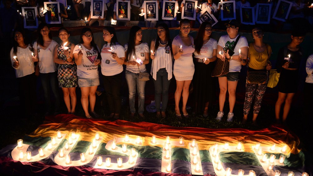 Protesters hold candles during a vigil inside the campus of the state university in Manila on Oct. 24, 2014, to coincide with the burial of murdered transgender woman, Jennifer Laude. (Photo by Ted Aljibe/AFP/Getty)
