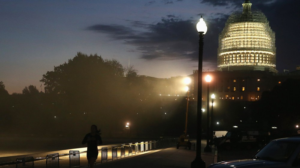 The sun begins to rise behind the dome of the US Capitol that is covered in scafollding for repairs, on Nov. 4, 2014 in Washington, DC.