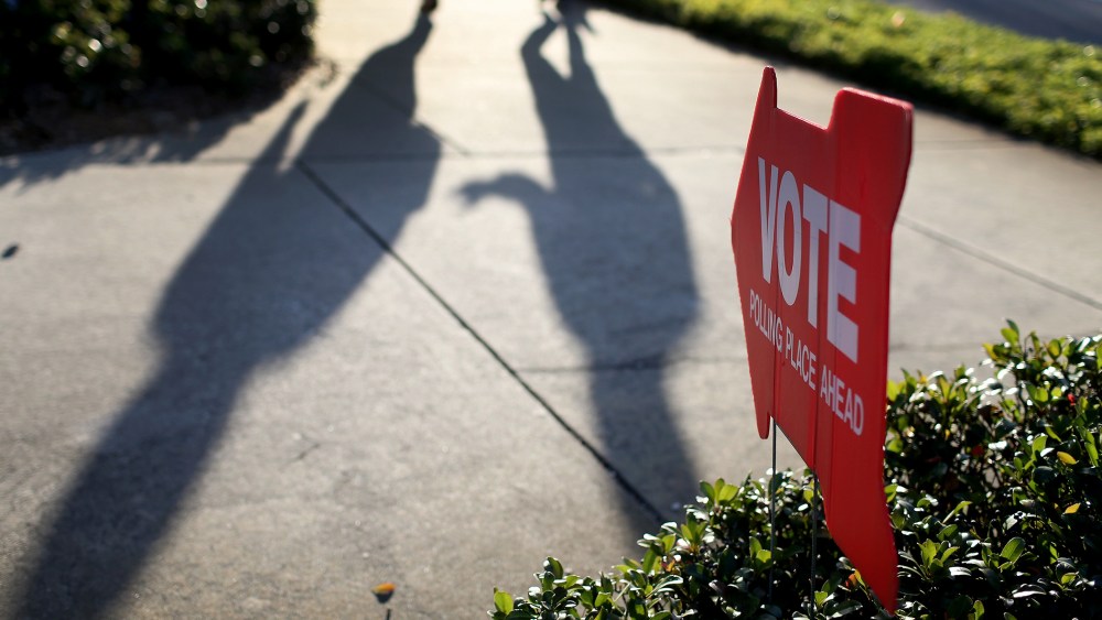 Voters cast shadows as they walk to the polling station past a sign pointing the way to The Coliseum where a polling station is setup on Nov. 4, 2014 in St Petersburg, Fla.