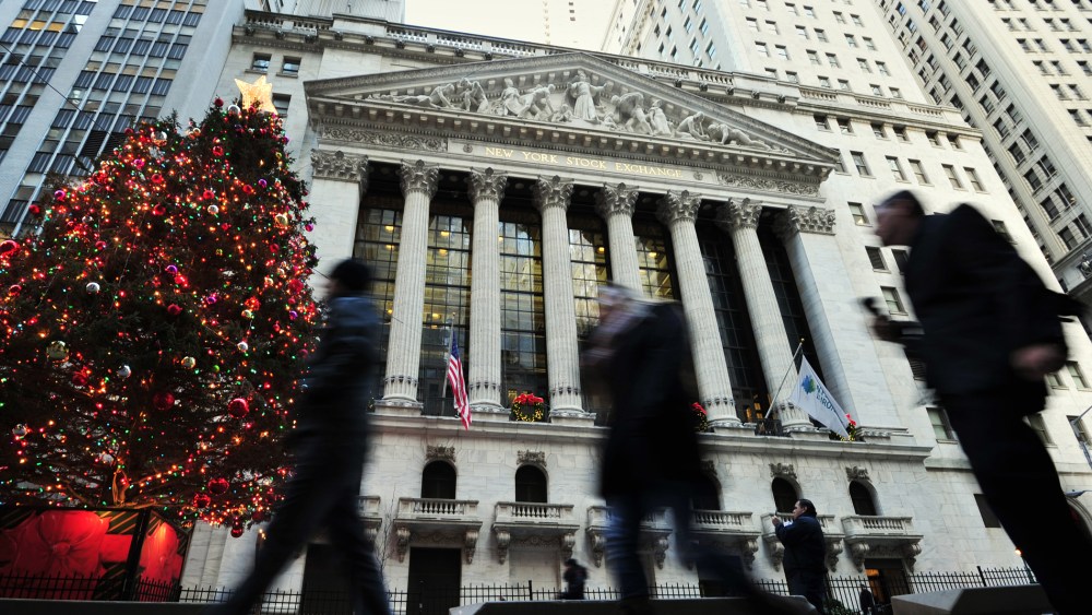 People walk by a Christmas tree in front of the New York Stock Exchange, Dec. 24, 2013 in New York.