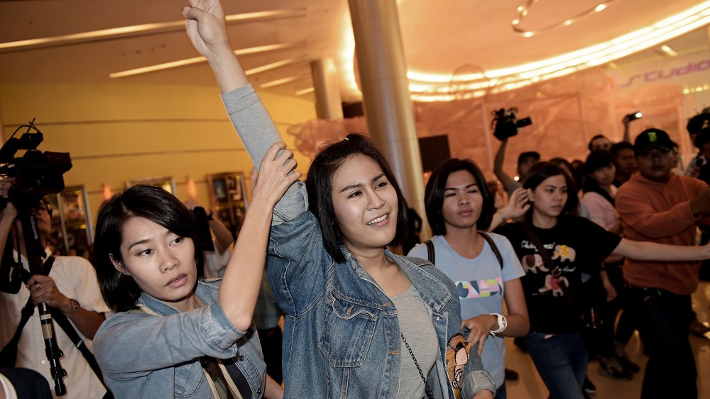 A Thai student flashes a three-finger salute as she is escorted out of a cinema hall by plainclothes female police officers in Bangkok on Nov. 20, 2014.