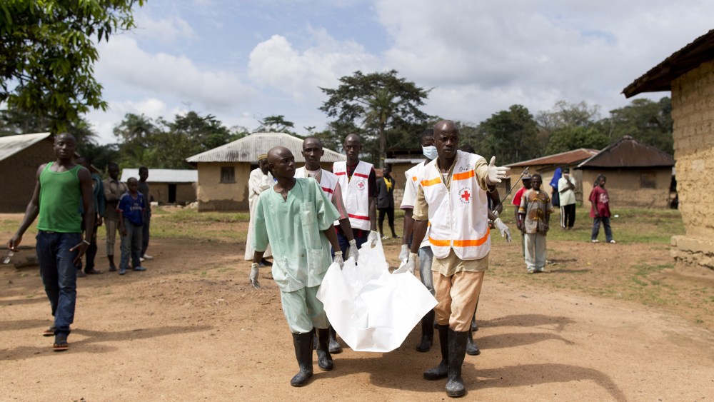 Health workers from Guinea's Red Cross carry the body of a victim of the Ebola virus in Momo Kanedou in Guinea on Nov. 19, 2014. (Photo by Kenzo Tribouillard/AFP/Getty)