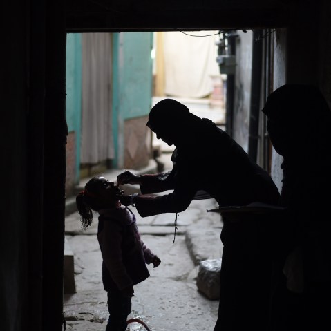 A Pakistani health worker (R) administers the polio vaccine to a child during a vaccination campaign in Rawalpindi on Dec. 9, 2014. (Photo by Farooq Naeem/AFP/Getty)