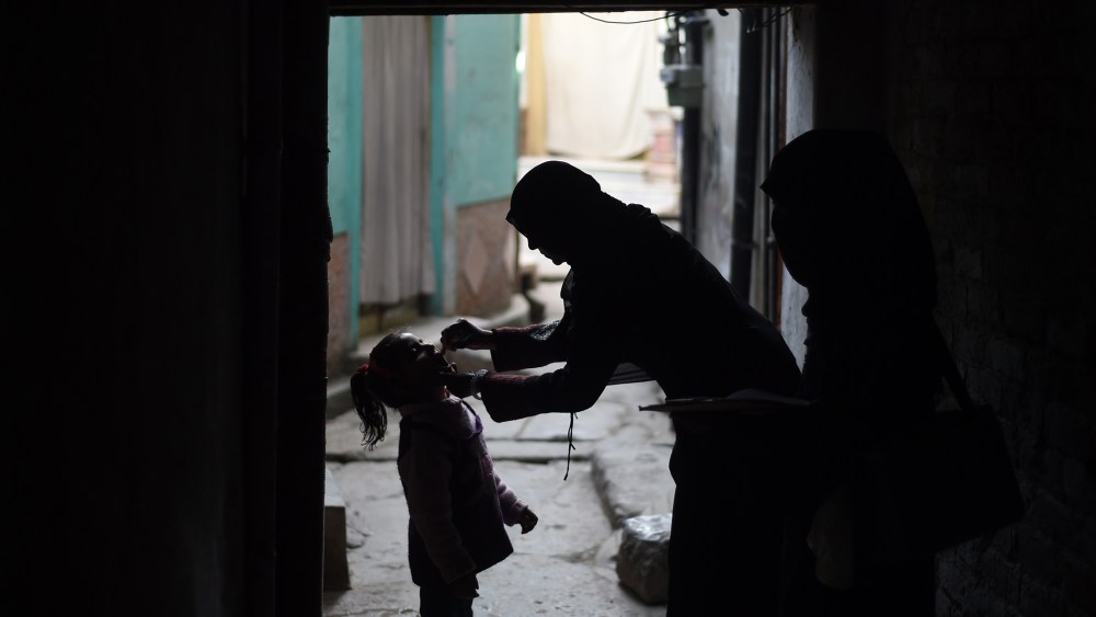 A Pakistani health worker (R) administers the polio vaccine to a child during a vaccination campaign in Rawalpindi on Dec. 9, 2014. (Photo by Farooq Naeem/AFP/Getty)