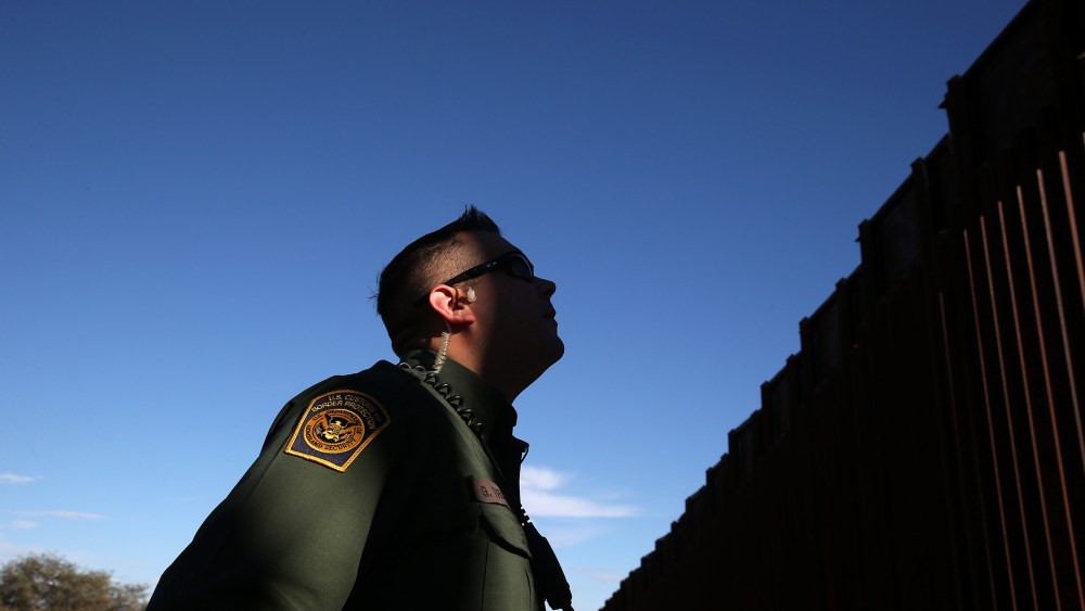 A U.S. Border Patrol agent stands next to the U.S.-Mexico border fence on Dec. 9, 2014 in Nogales, Ariz.