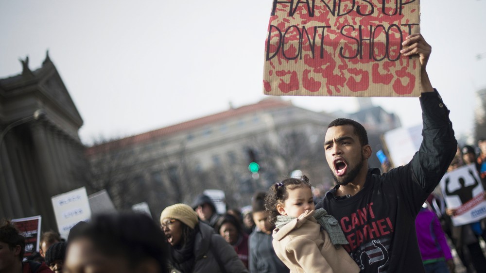 Ray Dickerson holds his one-year-old daughter Selina and a placard as he marches through the streets for the "Justice For All" march in Washington, DC, on Dec. 13, 2014. (Jim Watson/AFP/Getty)