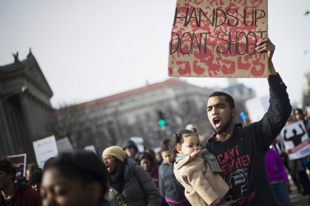Ray Dickerson holds his one-year-old daughter Selina and a placard as he marches through the streets for the "Justice For All" march in Washington, DC, on Dec. 13, 2014. (Jim Watson/AFP/Getty)