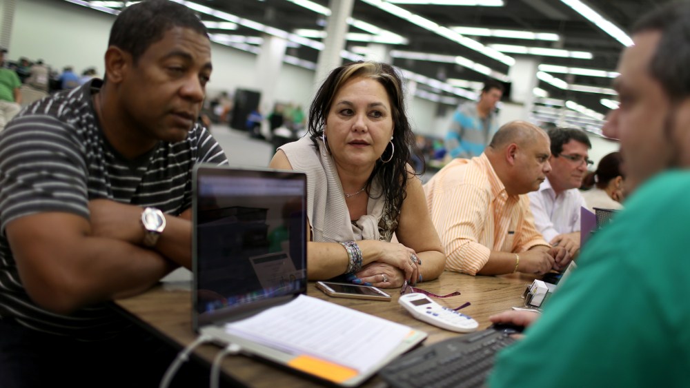 Jose Ramirez and Mariana Silva speak with Yosmay Valdivia, an agent from Sunshine Life and Health Advisors, as they discuss plans available from the Affordable Care Act on Dec. 15, 2014 in Miami, Fla. (Joe Raedle/Getty)