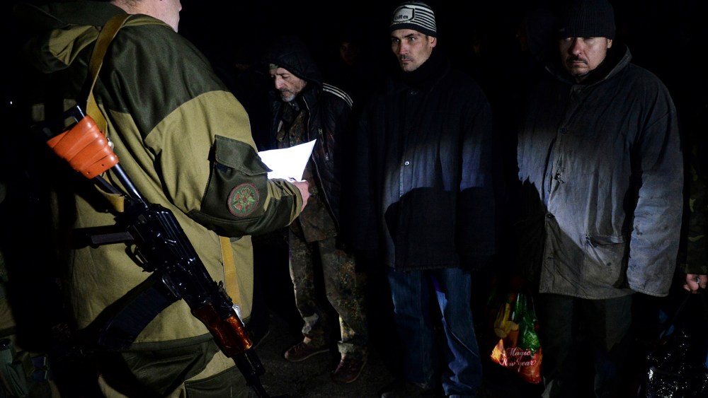 Ukrainian prisoners stand as a pro-Russian rebel holds a sheet of paper during procedures for a prisoner exchange with Ukraine on Dec. 26, 2014 in the eastern Ukrainian city of Yasinovataya, near Donetsk.