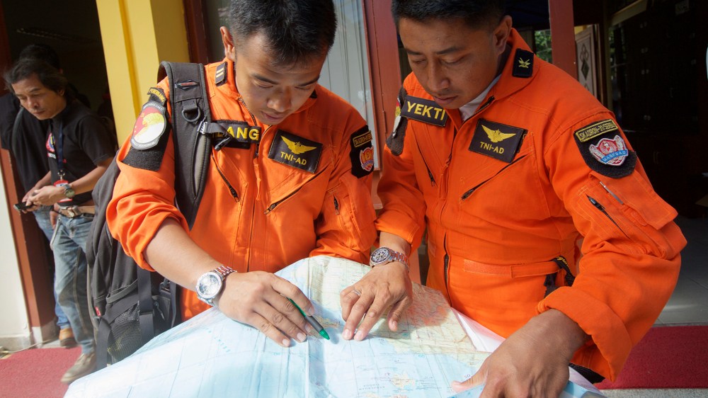 Indonesian Search and Rescue Helicopter pilots look over a map of the search area for debris from AirAsia Flight QZ8501 in the waters near Bangka Island, Indonesia. (Ed Wray/Getty)