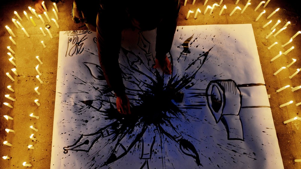 A Nepalese journalist draws a cartoon during a candlelight vigil in solidarity with the victims of an attack by armed gunmen on the offices of French satirical newspaper Charlie Hebdo on Jan. 9, 2015. (PRAKASH MATHEMA/AFP/Getty Images)