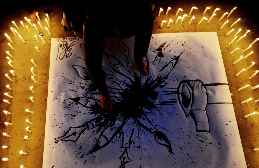 A Nepalese journalist draws a cartoon during a candlelight vigil in solidarity with the victims of an attack by armed gunmen on the offices of French satirical newspaper Charlie Hebdo on Jan. 9, 2015. (PRAKASH MATHEMA/AFP/Getty Images)