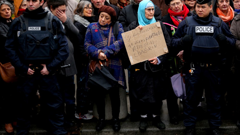 Amid tight security, a woman holds up a sign saying 'I am a Muslim. I come to share your grief' as members of the public pay respects at the funeral of Charlie Hebdo a cartoonist on Jan. 15, 2015 in Paris, France.  (Photo by Christopher Furlong/Getty)