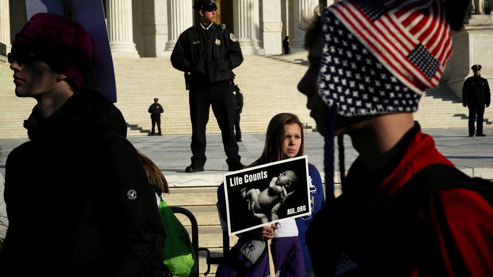 A pro-life activist holds a sign as she watches the annual March for Life passes by in front of the U.S. Supreme Court Jan. 22, 2015 in Washington, DC. (Photo by Alex Wong/Getty)