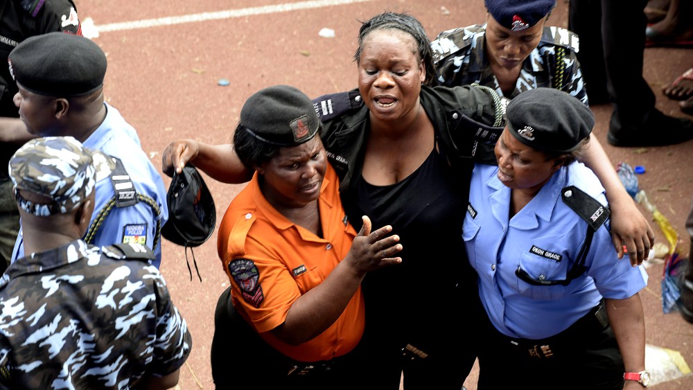 Policewomen help a colleague injured during fracas that broke out during a presidential campaign rally of Nigeria's main opposition All Progressives Congress (APC) at Taslim Balogun Stadium in Lagos on Jan. 30, 2015. (Photo by Pius Utomi Ekpei/AFP/Getty)