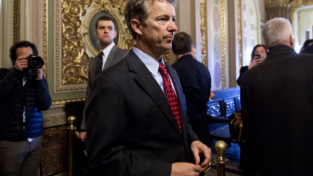 Rand Paul talks with a staff member as he walks to participate in a cloture vote at the US Capitol. Feb. 12, 2014.