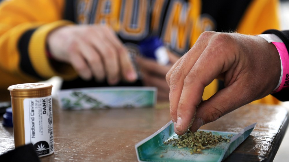 Shawn Holland, 21, breaks up a piece of marijuana to roll a joint during the High Times Cannabis Cup at the Denver Mart in Denver, Colo. on April 19, 2015.