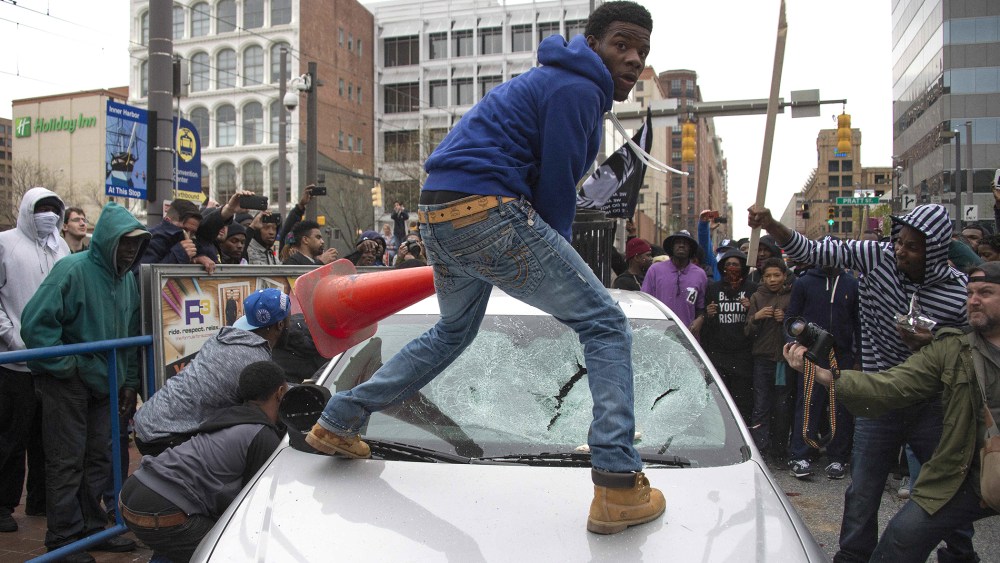 Demonstrators destroy the windshield of a Baltimore Police car as they protest the death Freddie Gray, an African American man who died of spinal cord injuries in police custody, in Baltimore, Md., April 25, 2015. (Photo by Jim Watson/AFP/Getty)