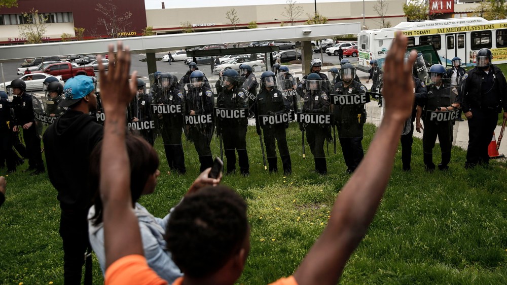 A protestors confronts Baltimore Police officers with his hands up near Mondawmin Mall on April 27, 2015 in Baltimore, Md.
