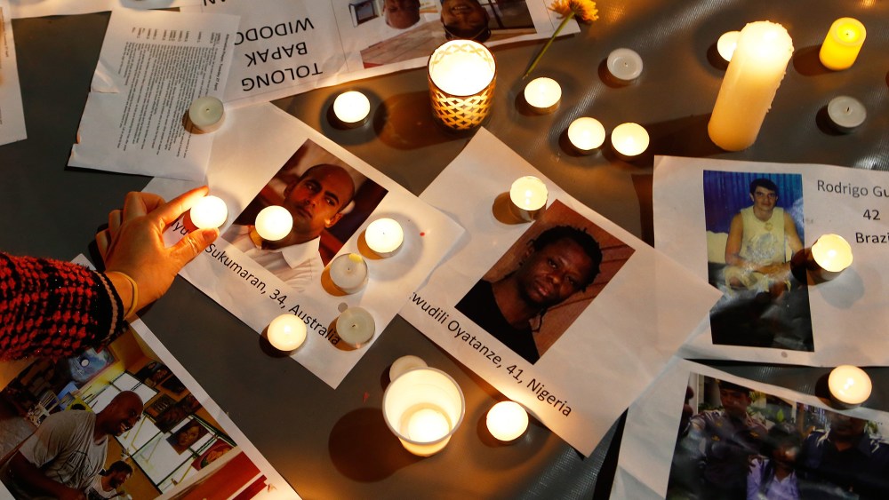 A woman places a candle on top of pictures of the prisoners to be executed in Indonesia, during a vigil at Martin Place on April 28, 2015 in Sydney, Australia. (Photo by Daniel Munoz/Getty)