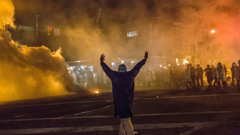 A protester walks through smoke as police enforce a mandatory, city-wide curfew of 10PM near the CVS pharmacy that was set on fire yesterday during rioting after the funeral of Freddie Gray, on April 28, 2015 in Baltimore, Md.
