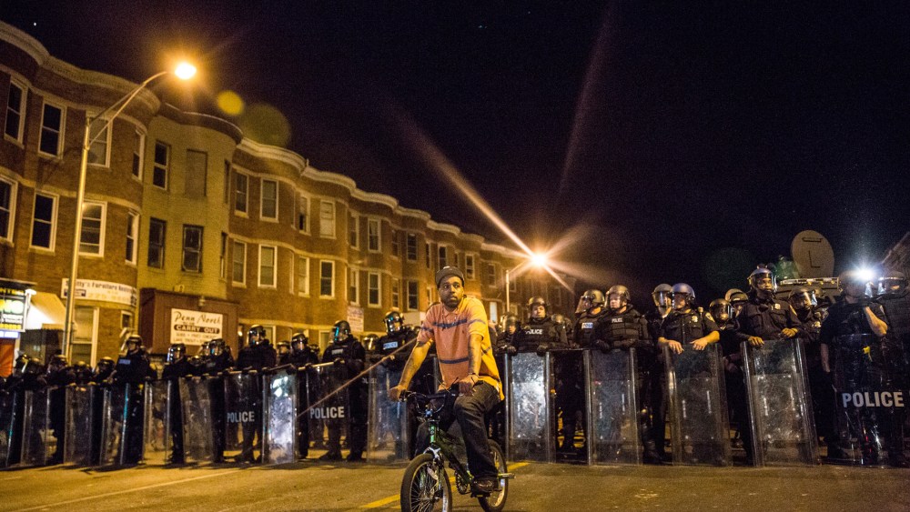 A protester sits in front of riot police minutes before a mandatory, city-wide curfew of 10 p.m. near the CVS pharmacy that was set on fire yesterday during rioting after the funeral of Freddie Gray, on April 28, 2015 in Baltimore, Md.