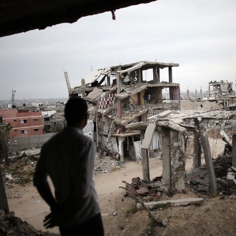 A Palestinian man stands amid the rubble looking at a building opposite to him, on May 11, 2015, which was destroyed during the 50-day war between Israel and Hamas militants in the summer of 2014, in the Eastern Gaza City Shujaiya neighborhood.