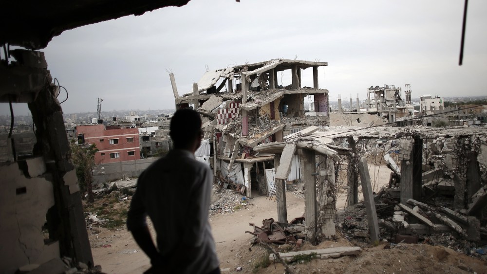 A Palestinian man stands amid the rubble looking at a building opposite to him, on May 11, 2015, which was destroyed during the 50-day war between Israel and Hamas militants in the summer of 2014, in the Eastern Gaza City Shujaiya neighborhood.