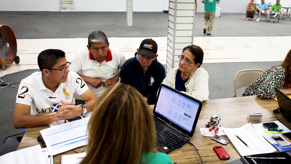 An insurance agent helps a family as they try to purchase health insurance under the Affordable Care Act in Miami, Florida, Mar. 20, 2014.