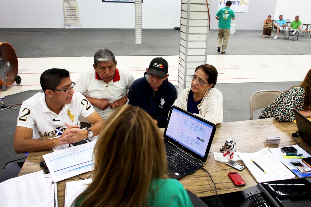 An insurance agent helps a family as they try to purchase health insurance under the Affordable Care Act in Miami, Florida, Mar. 20, 2014.