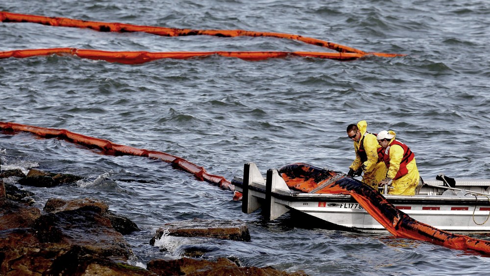 People with Garner Environmental Services work with oil booms that line the coast of East Beach on the Houston Ship Channel on March 25, 2014 in Galveston, Texas.