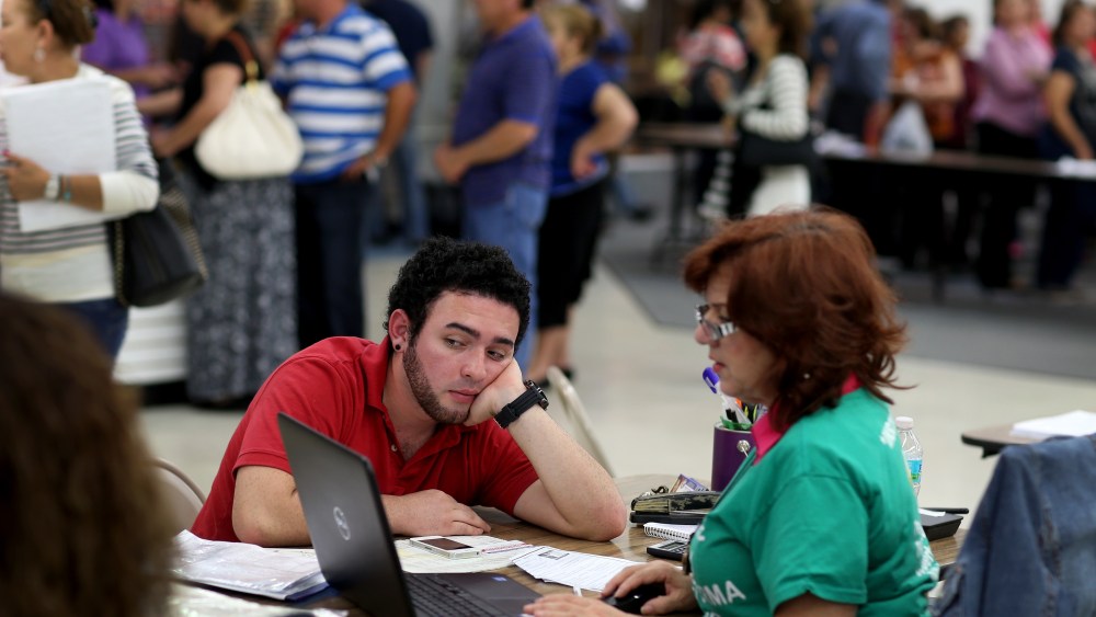 Andres Cuartas sits with an agent with Sunshine Life and Health Advisors as he purchases a health insurance plan under Obamacare in Miami, March 31, 2014.