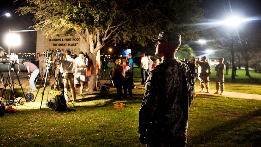 A soldier watches over media as they prepare for a press conference about the shooting at Fort Hood, April 2, 2014.