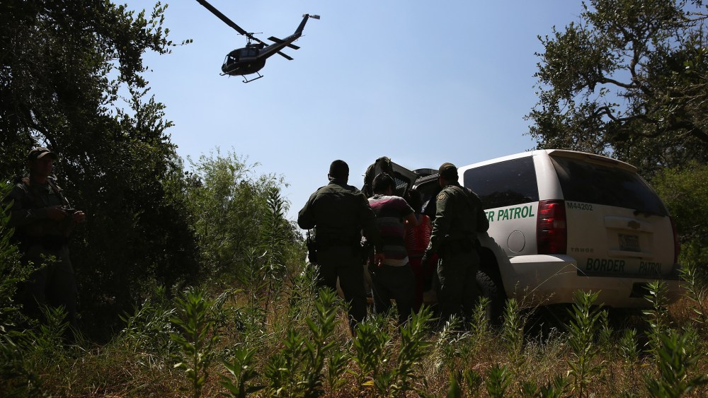 U.S. Border Patrol agents detain undocumented immigrants with the help of helicopter support from the U.S. Office of Air and Marine north of the U.S.-Mexico border on Aug. 6, 2015 near Falfurrias, Texas. (Photo by John Moore/Getty)
