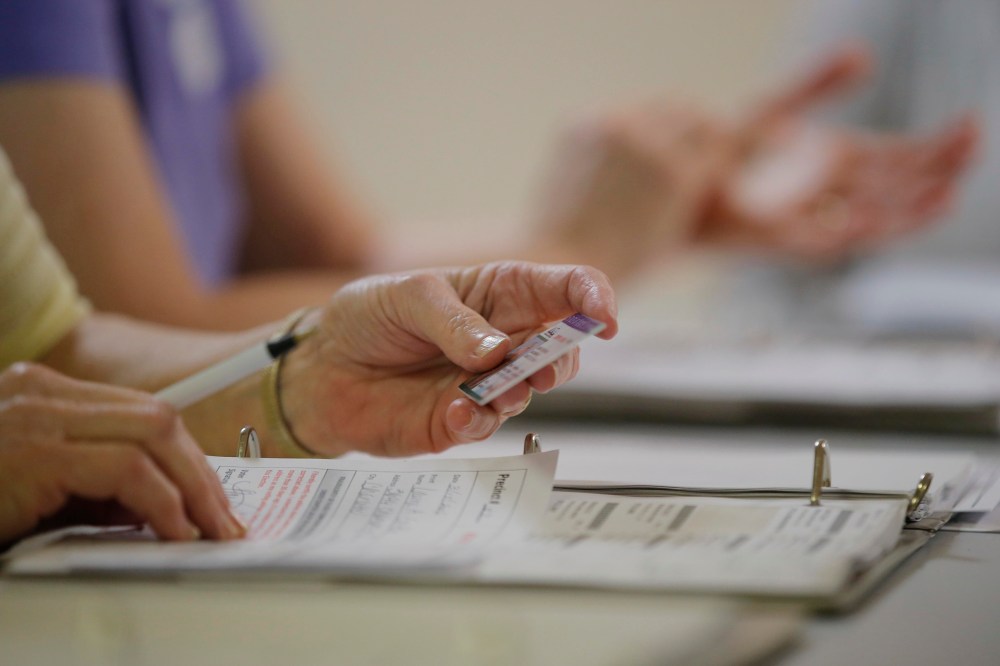 An election worker checks a voter's drivers license as North Carolina's controversial "Voter ID" law goes into effect for the state's presidential primary election at a polling place, March 15, 2016,  in Charlotte, N.C. (Photo by Chris Keane/Reuters)