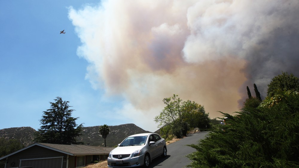 Smoke rises as the southeast flank of the Cocos fire bears down on houses near Del Dios Highway on May 15, 2014 near San Marcos, California.